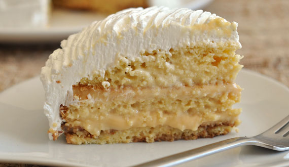 Una porción de torta de tres leches decorada con crema y fresas.